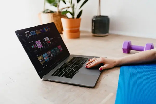 A hand reaching over a yoga mat to use a laptop touchpad.