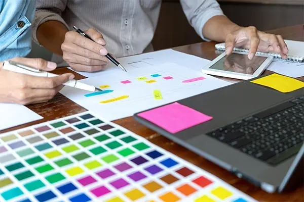 People creating a design on paper while checking a tablet computer.