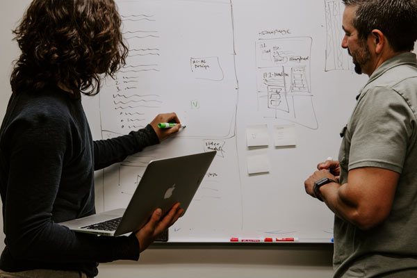 Two people standing in front of a whiteboard