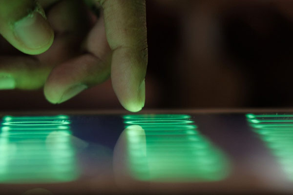 Agoslun o law yn rhyngweithio â rhyngwyneb sgrin gyffwrdd gwyrdd disglair.