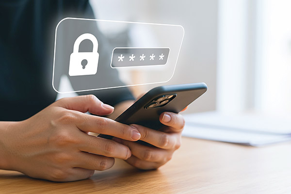 Dwylo yn dal ffôn clyfar gyda chlo a symbolau cyfrinair uwchben y sgrin.