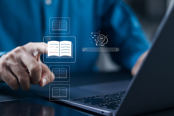 Unigolyn yn defnyddio gliniadur gyda eiconau digidol o lyfrau agored a bar chwilio yn arnofio o flaen y sgrin